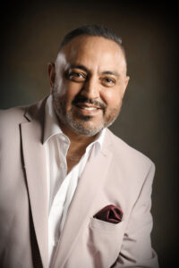 Man in a cream suit with a brown back ground