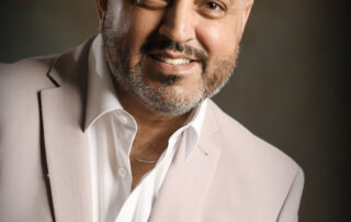 Man in a cream suit with a brown back ground
